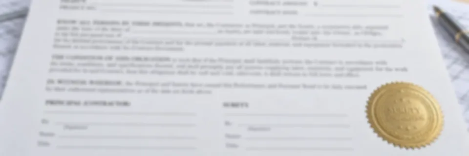 A performance and payment bond form on a desk with rolled drawings and a fountain pen, carrying a gold surety seal, a mid-rise building under construction behind it